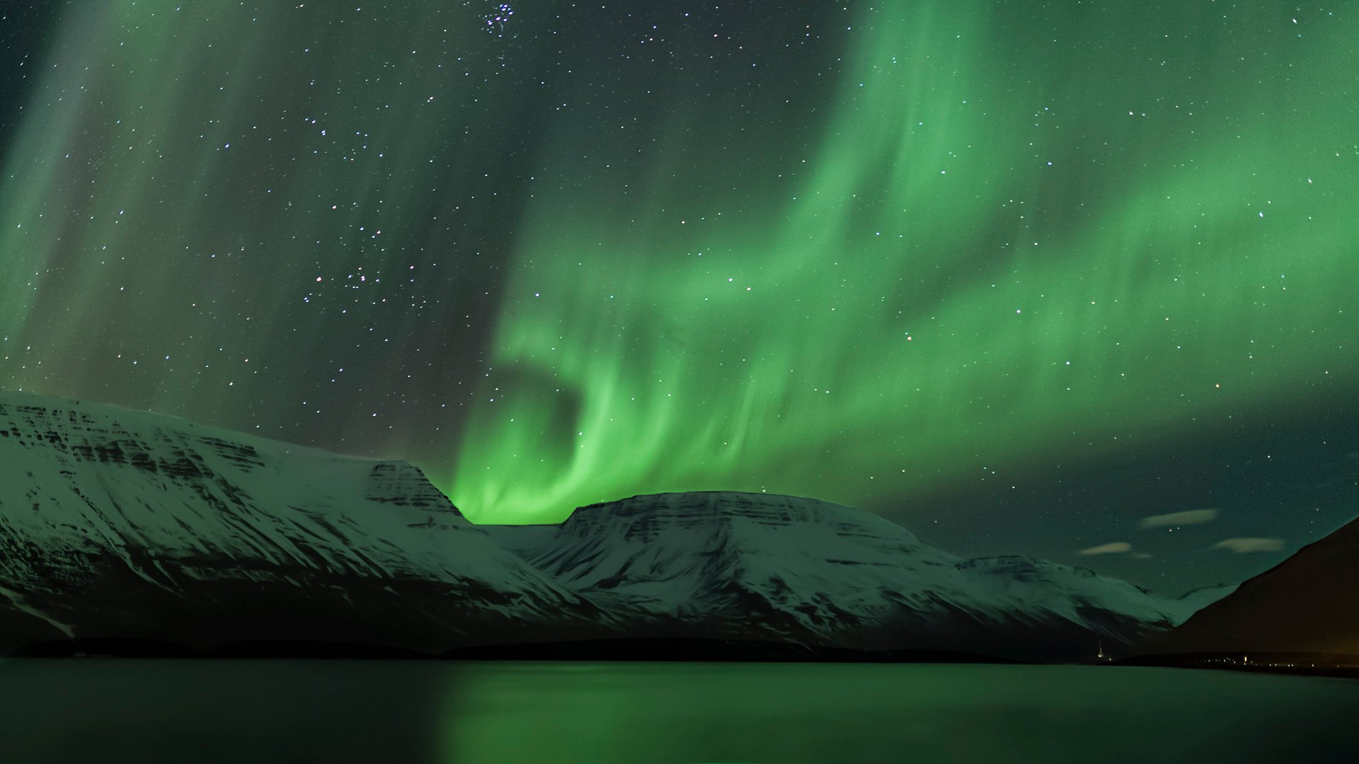 Aurora over snow covered mountains near Súgandafjörður
